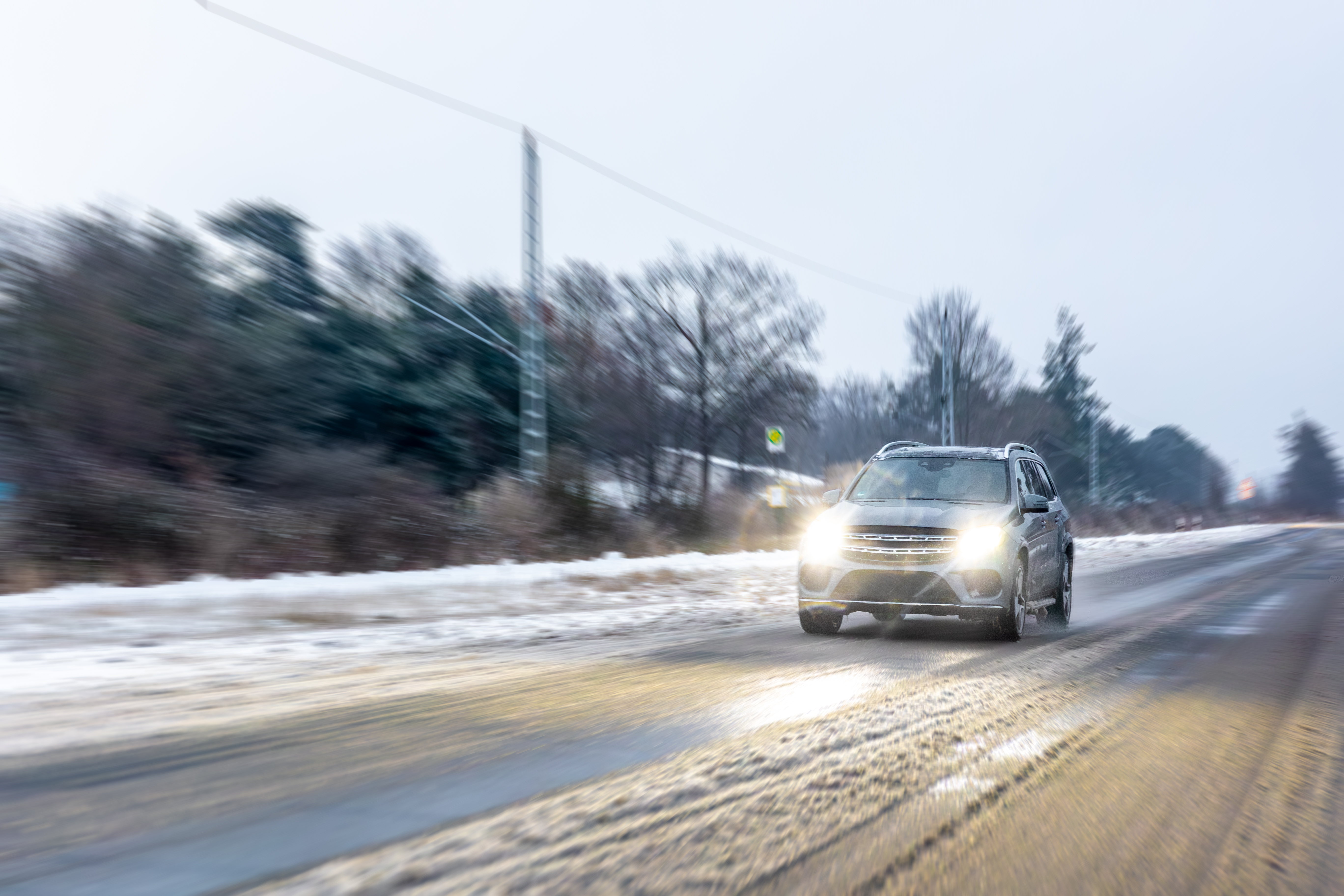 car-speeds-along-winter-highway-with-headlights-winter-roadtrip-motion.jpg
