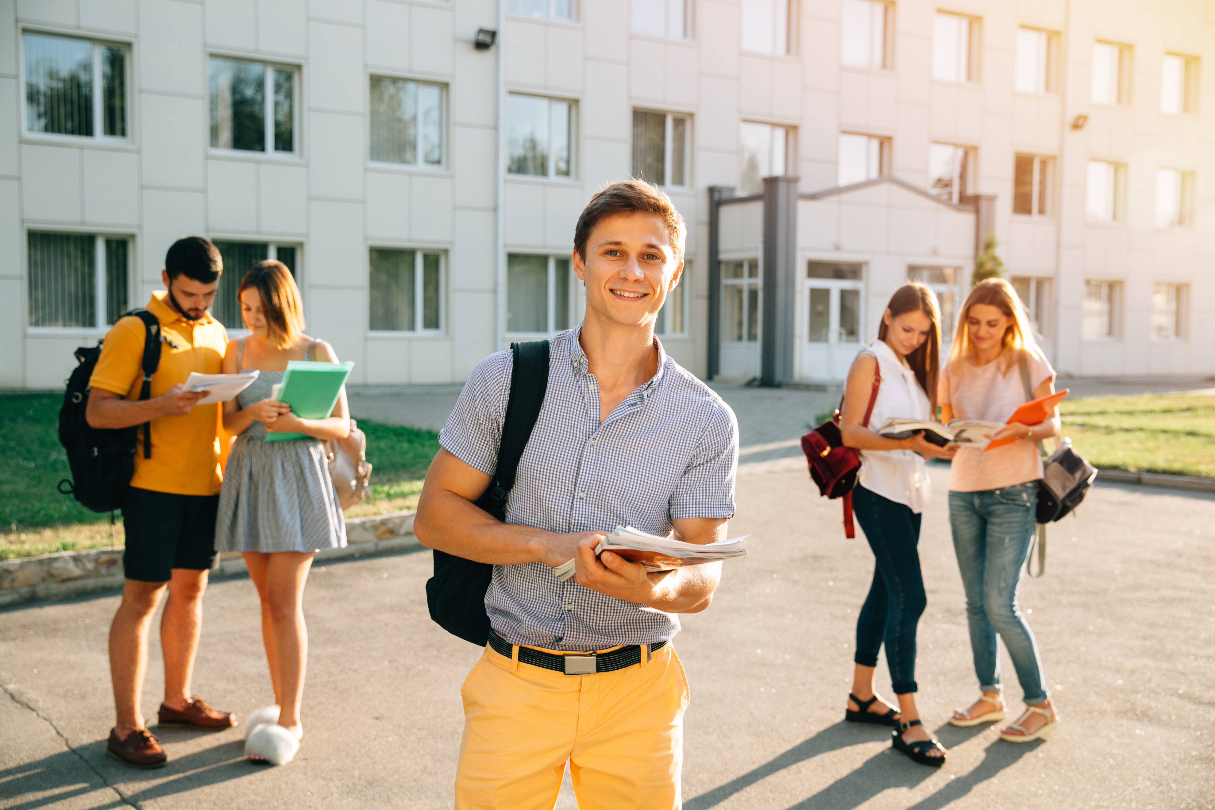 happy-student-with-note-books-backpack-smiling-while-standing.jpg