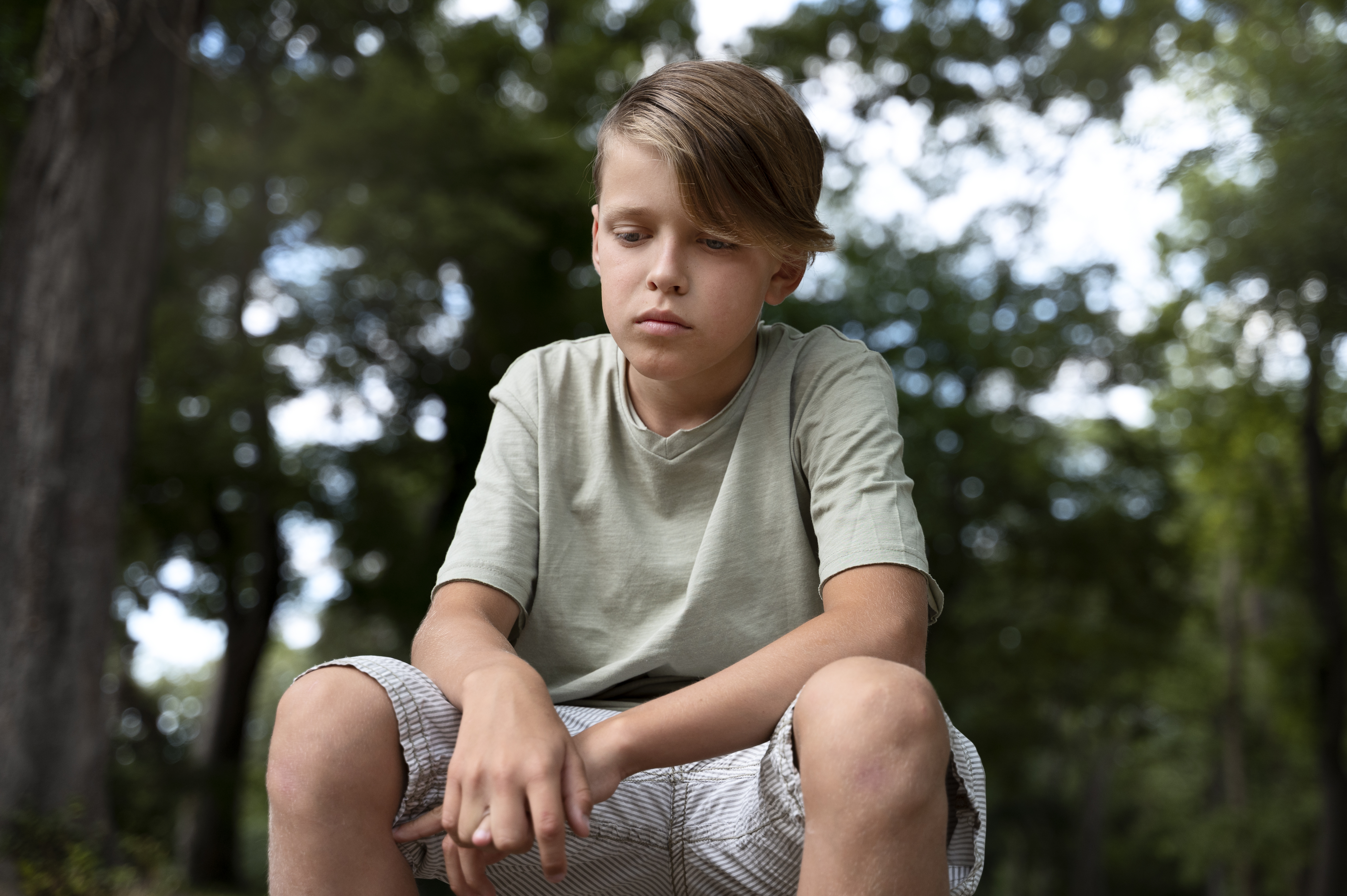 low-angle-sad-boy-sitting-outdoors.jpg
