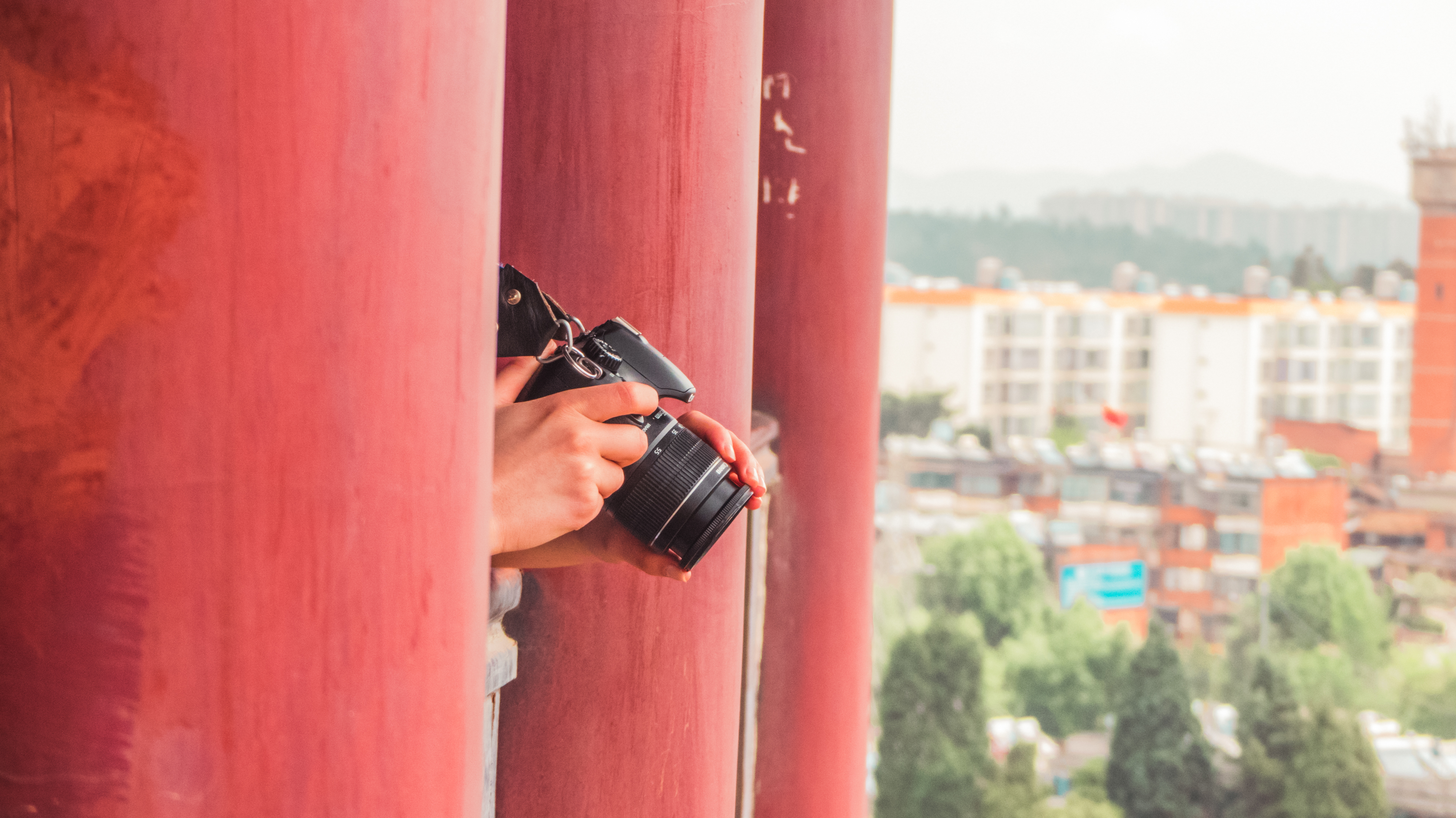 person-standing-red-pillars-holding-camera.jpg