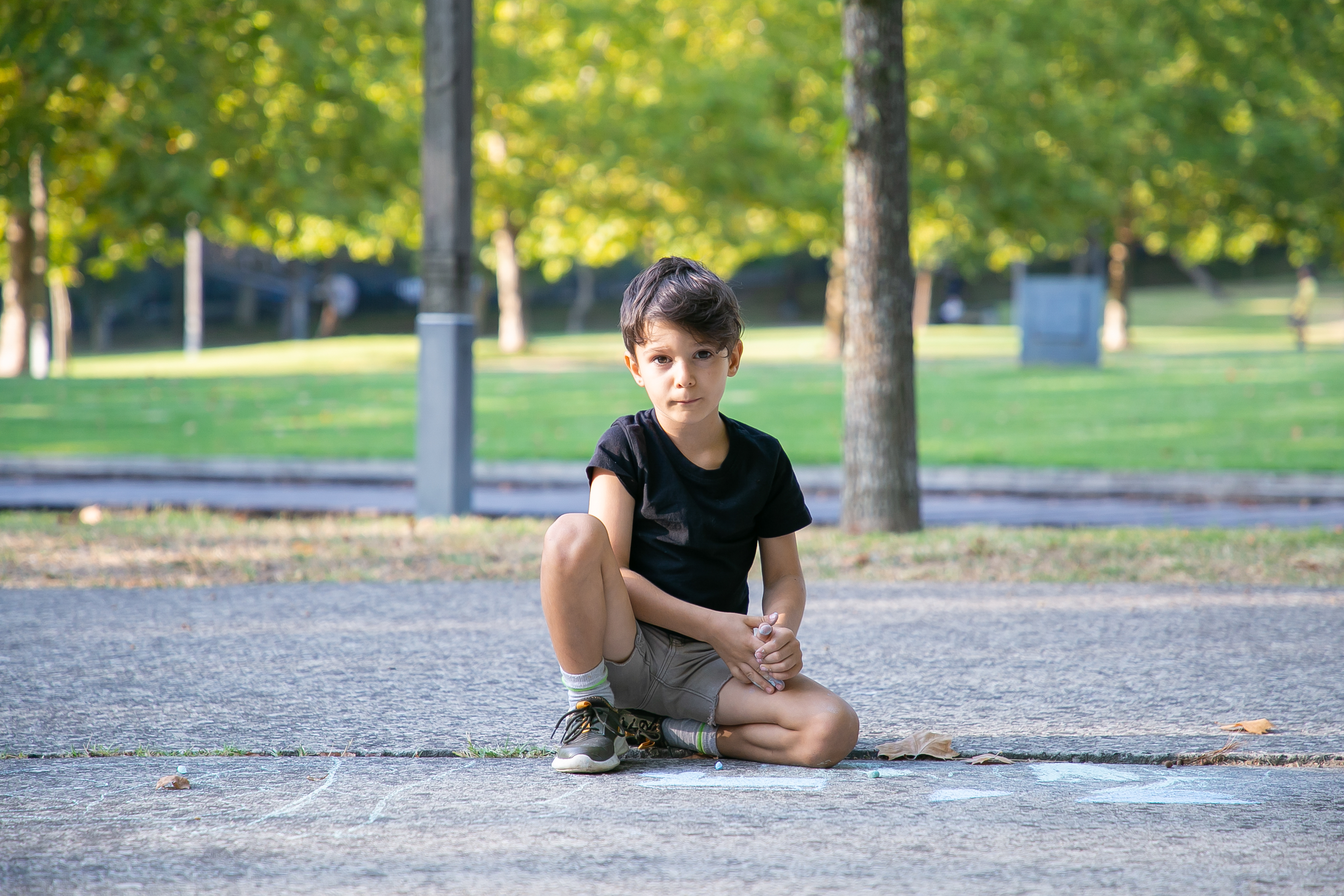 serious-cute-boy-sitting-drawing-asphalt-with-colorful-pieces-chalks-front-view-childhood-creativity-concept.jpg